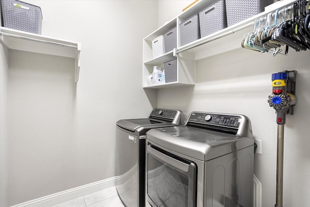 laundry room featuring laundry area, tile patterned flooring, washing machine and clothes dryer, and baseboards