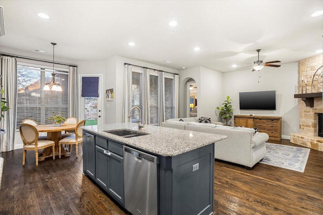 kitchen with arched walkways, dark wood-type flooring, a fireplace, a sink, and stainless steel dishwasher