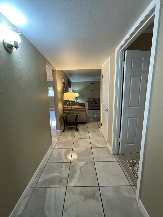 hall featuring marble finish floor, a textured ceiling, and baseboards