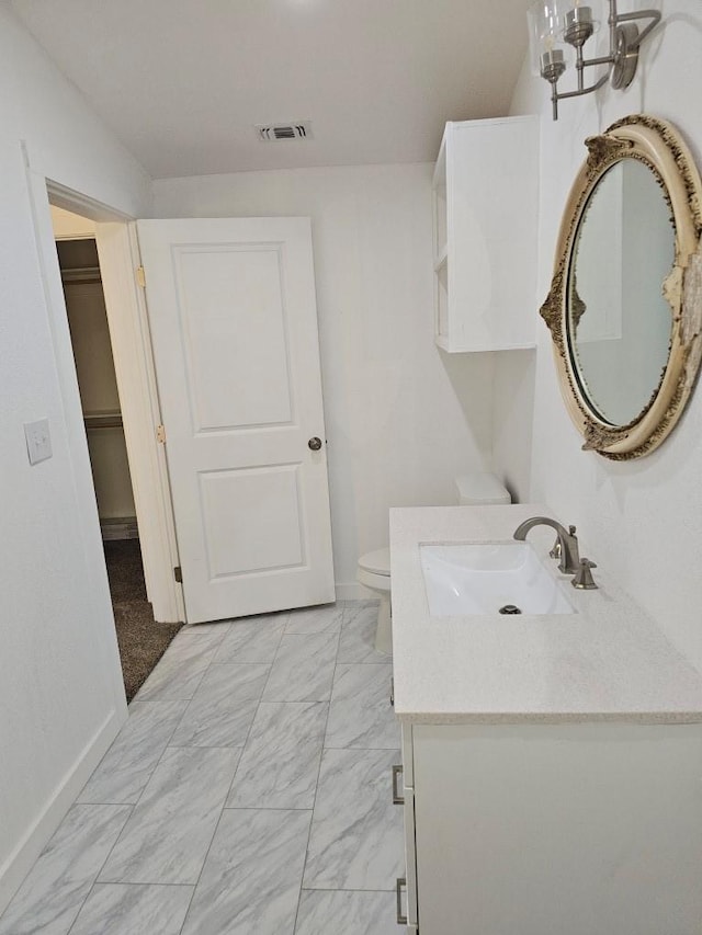 bathroom with baseboards, visible vents, toilet, marble finish floor, and vanity