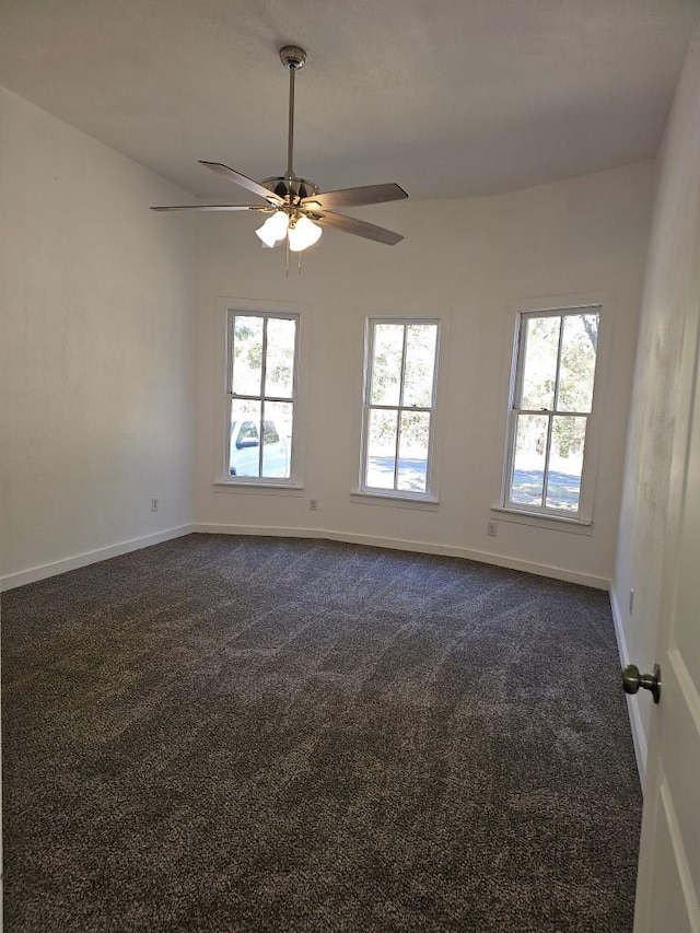 unfurnished room with dark colored carpet, a wealth of natural light, and baseboards