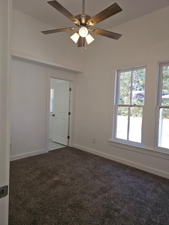 carpeted empty room featuring a ceiling fan and baseboards