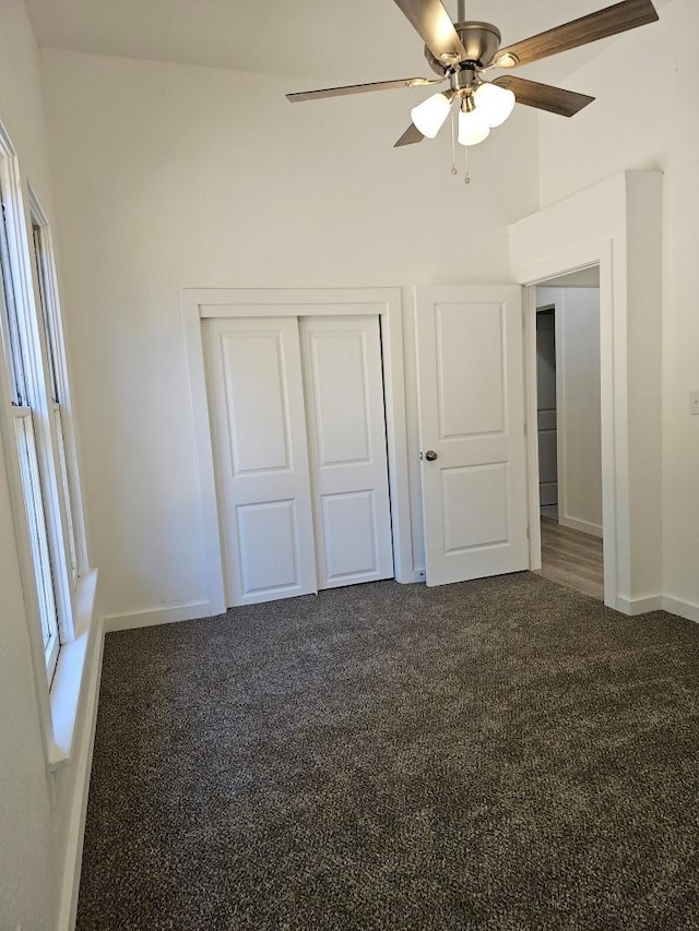 unfurnished bedroom with carpet floors, ceiling fan, baseboards, and a closet