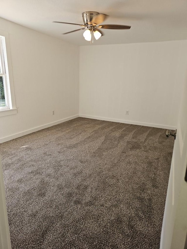 carpeted spare room with a ceiling fan and baseboards