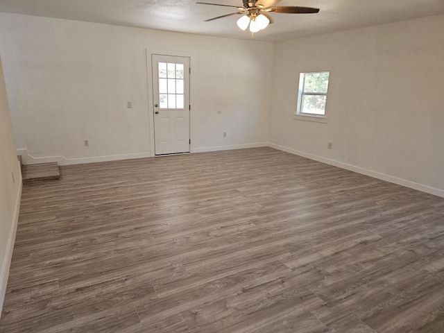 spare room featuring dark wood-style floors, ceiling fan, and baseboards