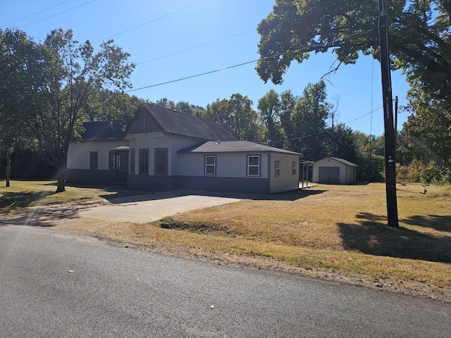 view of front of house featuring an outbuilding, a detached garage, concrete driveway, stucco siding, and a front yard