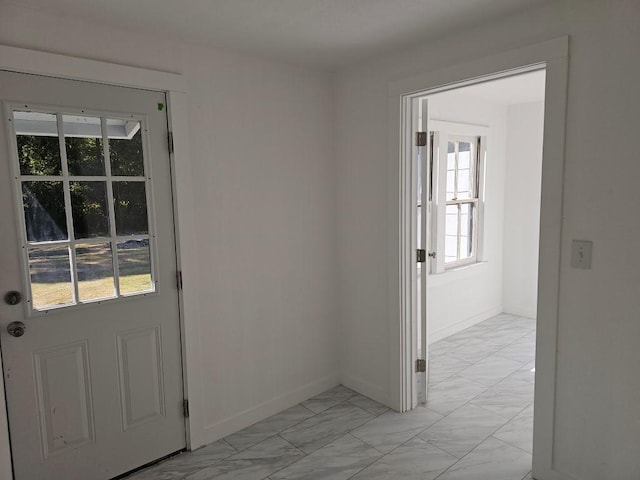 entryway with marble finish floor and baseboards