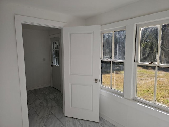 doorway featuring marble finish floor and baseboards