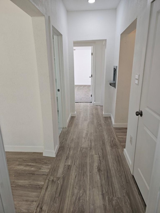 hallway featuring wood finished floors and baseboards