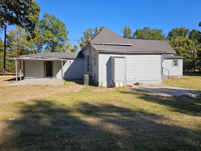 rear view of property with a shingled roof, a yard, a patio, and central AC unit