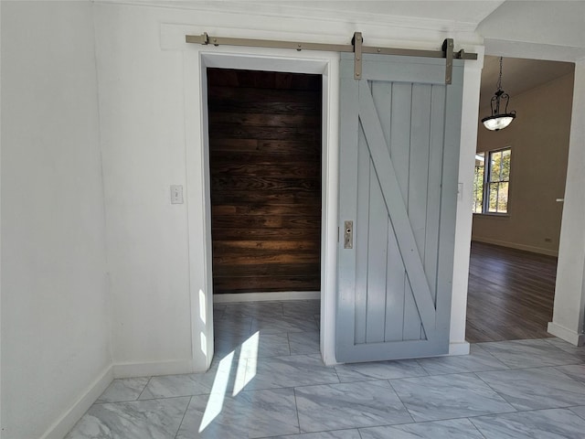 interior space with marble finish floor, a barn door, and baseboards