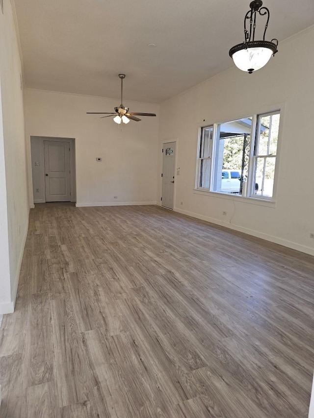 unfurnished living room featuring a ceiling fan, baseboards, and wood finished floors