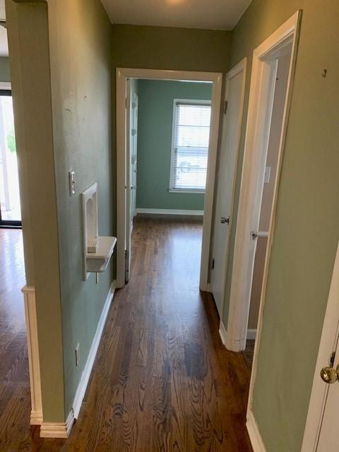 hall featuring dark wood-type flooring and baseboards