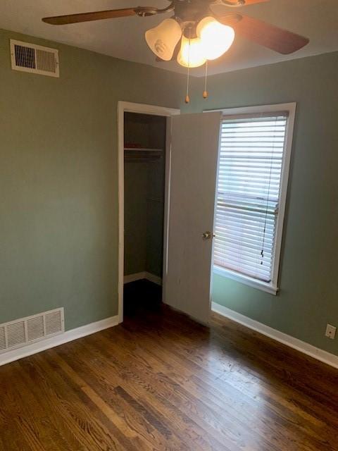 unfurnished bedroom with a closet, wood finished floors, visible vents, and baseboards