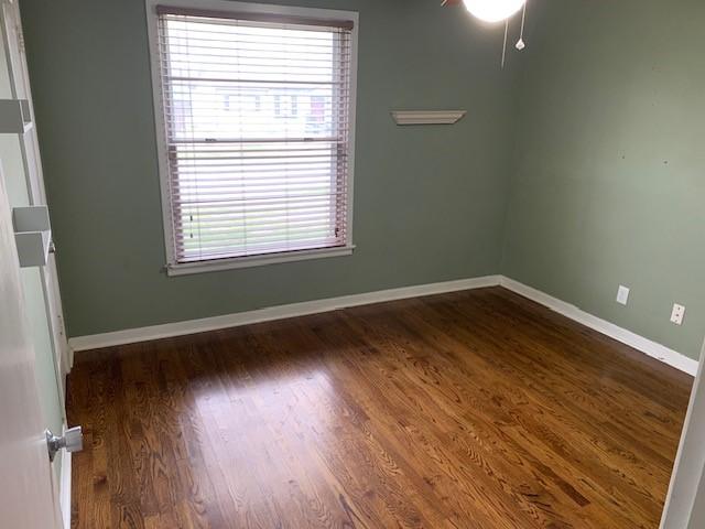 spare room featuring dark wood-style floors and baseboards