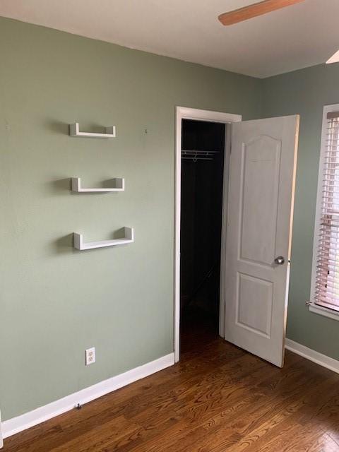 unfurnished bedroom with a closet, wood finished floors, and baseboards