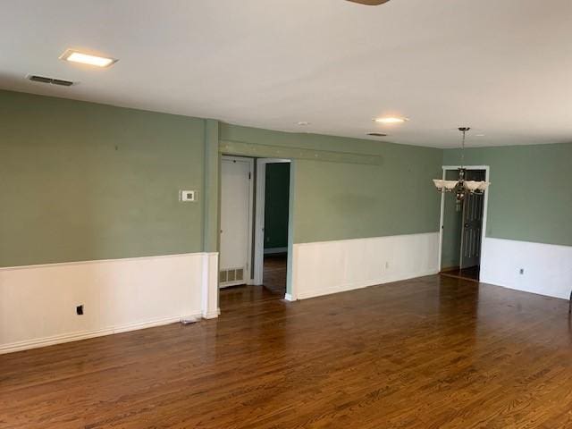 spare room featuring a chandelier, visible vents, and wood finished floors