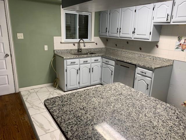 kitchen featuring a sink, white cabinets, baseboards, marble finish floor, and dishwasher