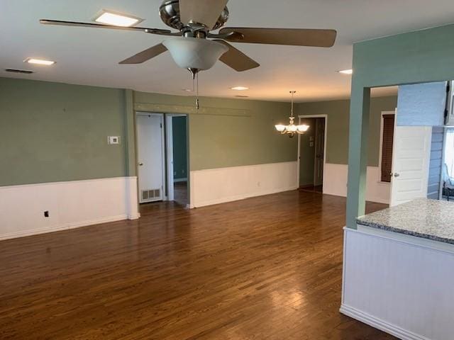 unfurnished room with dark wood-style flooring, visible vents, and ceiling fan with notable chandelier