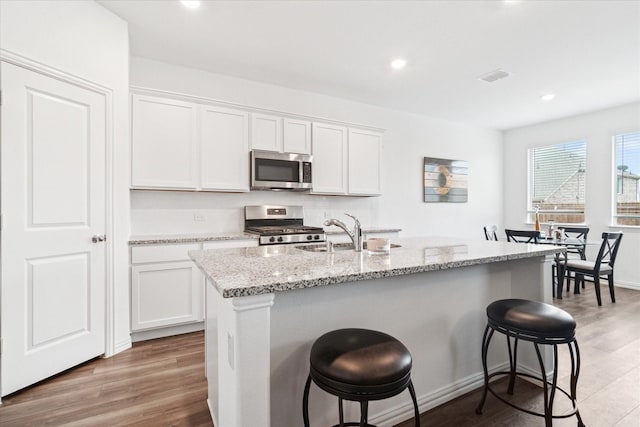 kitchen featuring light wood-style floors, stainless steel appliances, a sink, and a kitchen breakfast bar