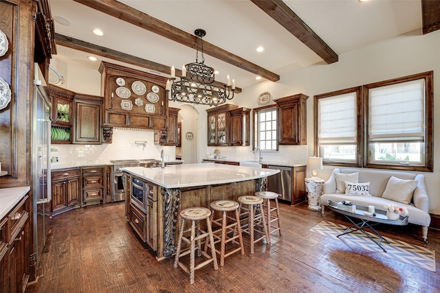 140 Manor Dr, Heath, TX 75032 - kitchen featuring appliances with stainless steel finishes, dark wood finished floors, a breakfast bar, beamed ceiling, and decorative backsplash