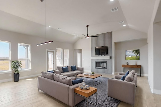 living area featuring recessed lighting, visible vents, a large fireplace, and light wood finished floors