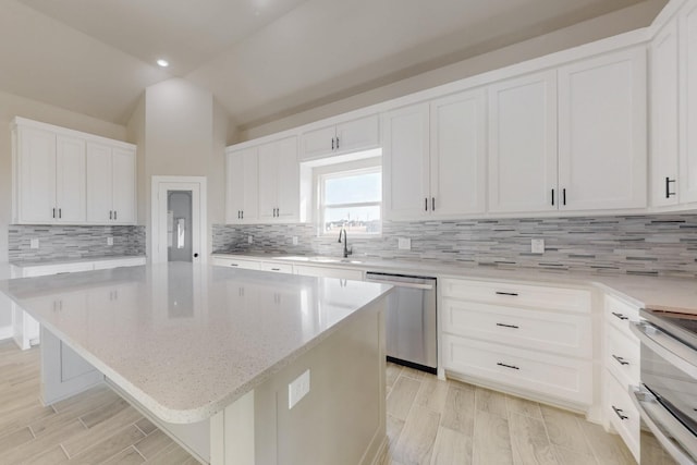 kitchen featuring lofted ceiling, dishwasher, a center island, and white cabinetry