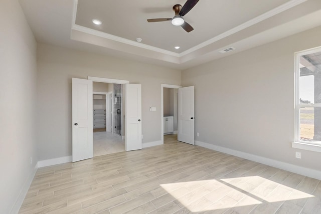 unfurnished bedroom featuring a raised ceiling, baseboards, and light wood-type flooring