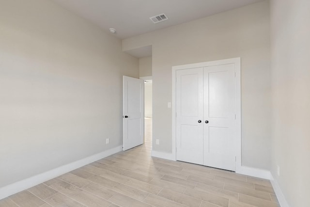 unfurnished bedroom with baseboards, visible vents, a closet, and wood tiled floor