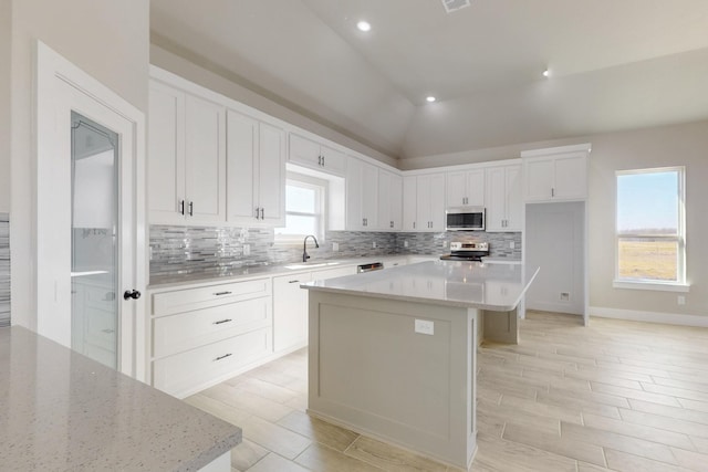 kitchen featuring a sink, stainless steel appliances, backsplash, and white cabinetry