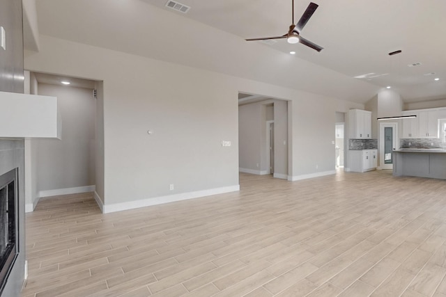 unfurnished living room with visible vents, light wood-style floors, a fireplace, ceiling fan, and vaulted ceiling