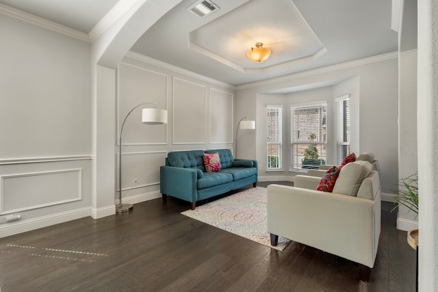 living room with visible vents, a decorative wall, dark wood finished floors, and ornamental molding