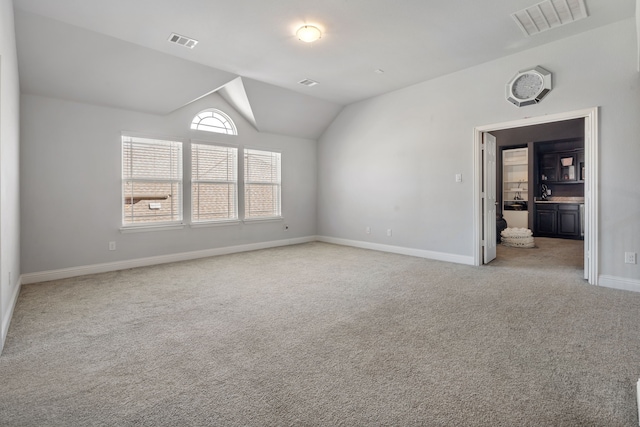 unfurnished room with vaulted ceiling, carpet flooring, visible vents, and baseboards