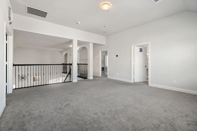 carpeted spare room featuring vaulted ceiling, visible vents, and baseboards