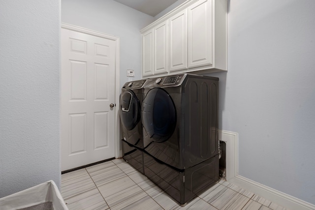 laundry room featuring cabinet space, baseboards, washer and dryer, and light tile patterned flooring