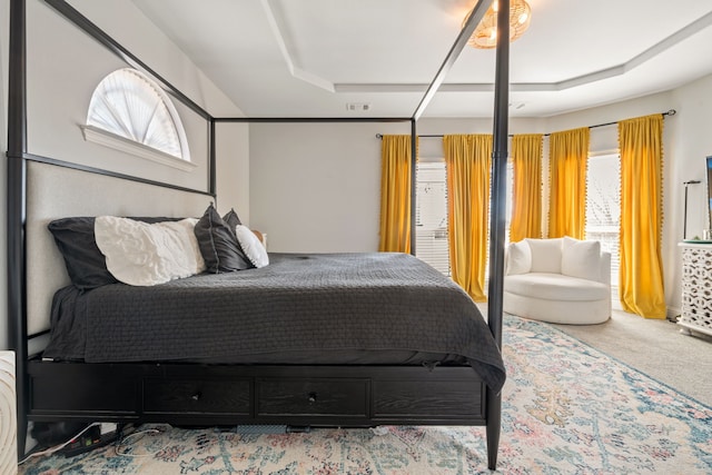 carpeted bedroom featuring a tray ceiling, multiple windows, and visible vents