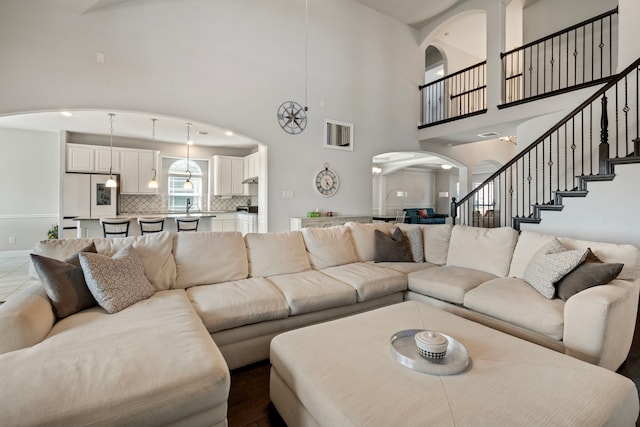 living room featuring a high ceiling, stairs, and arched walkways