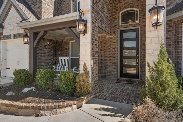 property entrance with an attached garage, brick siding, and a porch