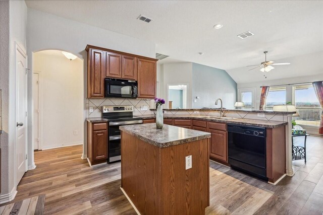 kitchen featuring visible vents, black appliances, a sink, backsplash, and arched walkways