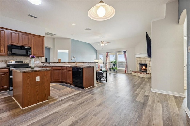 kitchen with a fireplace, a sink, black appliances, open floor plan, and backsplash