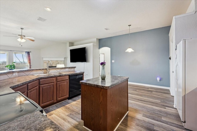 kitchen featuring dishwasher, freestanding refrigerator, electric stove, arched walkways, and a sink