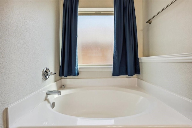 bathroom featuring a garden tub and a textured wall