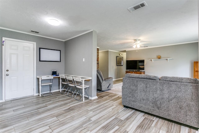 living room with wood finish floors, visible vents, crown molding, and ceiling fan