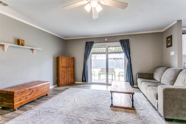 living room with ornamental molding, wood finished floors, visible vents, and baseboards