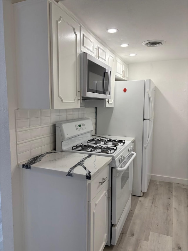 kitchen featuring tasteful backsplash, stainless steel microwave, visible vents, light wood-style floors, and white range with gas cooktop