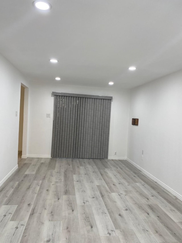 spare room with baseboards, wood finished floors, and recessed lighting