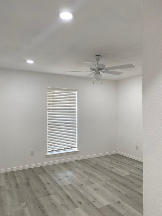 empty room with baseboards, wood finished floors, and recessed lighting