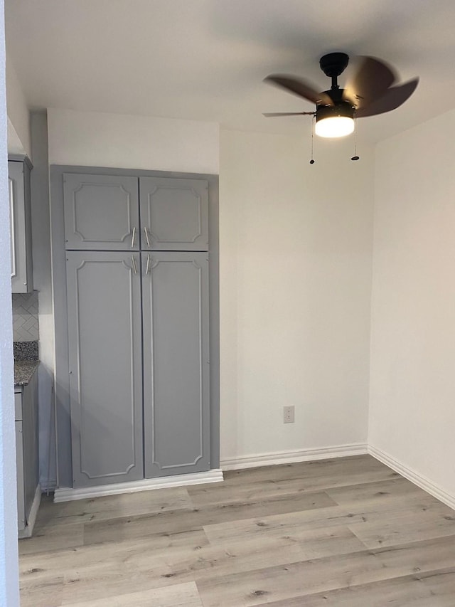 unfurnished bedroom featuring a ceiling fan, a closet, light wood-style flooring, and baseboards