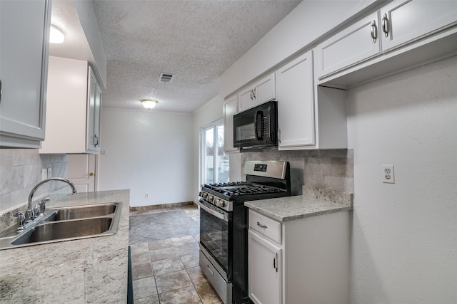 kitchen featuring visible vents, a sink, light countertops, black microwave, and gas range