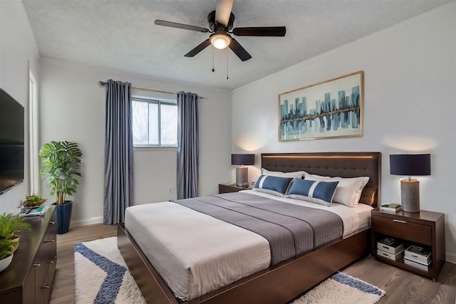 bedroom with wood finished floors, baseboards, ceiling fan, a textured ceiling, and crown molding